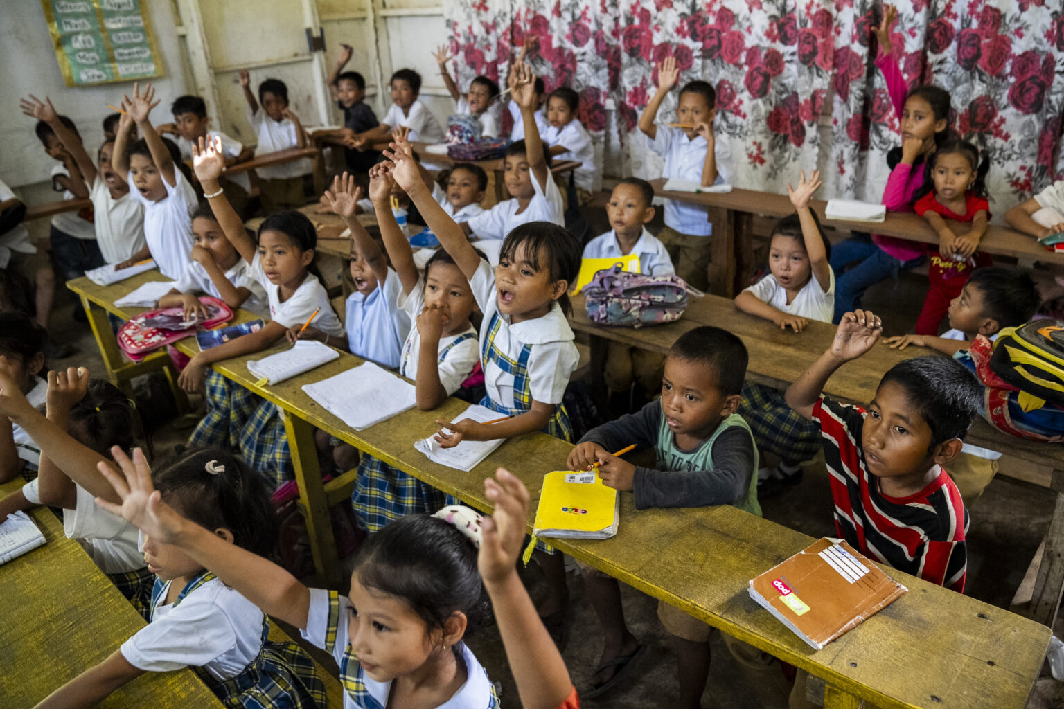 Children in a classroom in the Philippines raise their hands
